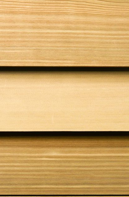 Close-up of light brown wooden planks arranged in horizontal layers, showing natural grain and thin gaps.