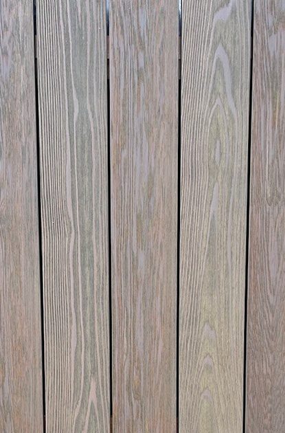 Vertical wooden planks with visible grain and small gaps; weathered gray-brown deck or fence surface.